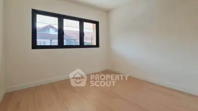 Bright empty room with wooden flooring and large window offering natural light