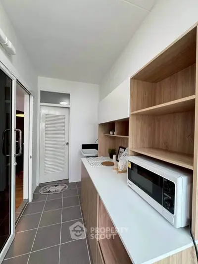Modern kitchen with sleek cabinetry and microwave, featuring a closed layout and stylish design.