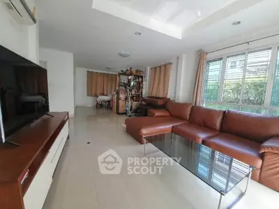 Spacious living room with modern brown leather sofa and large TV, perfect for relaxation.