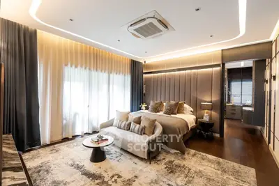 Luxurious bedroom with elegant decor and cozy seating area, featuring modern lighting and plush furnishings.