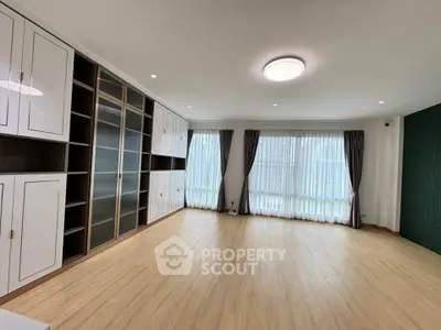 Spacious living room with built-in cabinets and large windows for natural light.