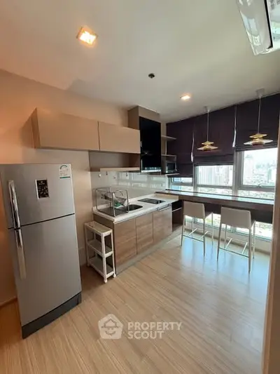 Modern kitchen with sleek design and city view, featuring a breakfast bar and stainless steel appliances.