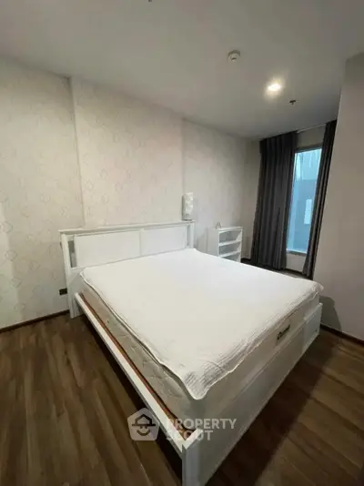 Spacious bedroom with modern decor and large window for natural light.