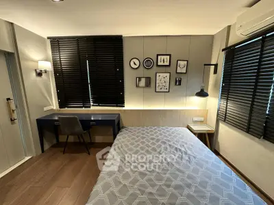 Modern bedroom with stylish decor and workspace, featuring wooden flooring and elegant lighting.