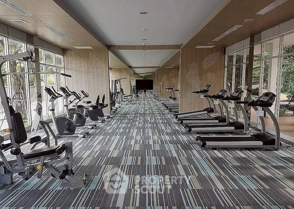 Spacious modern gym with state-of-the-art equipment and large windows for natural light.