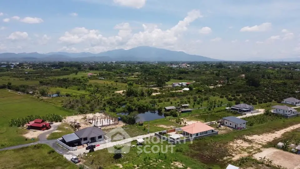 Scenic aerial view of countryside homes with mountain backdrop, showcasing serene rural living.