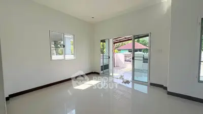 Spacious living room with large windows and sliding doors leading to a balcony, offering abundant natural light.