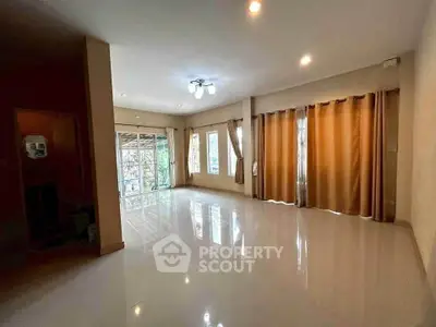 Spacious living room with large windows and elegant curtains, perfect for natural light and comfort.