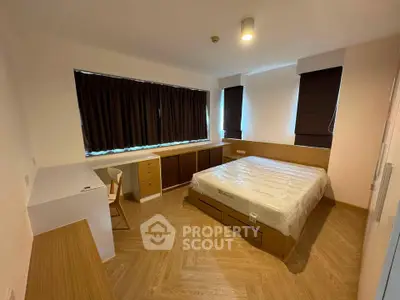 Spacious bedroom with modern furnishings and large window for natural light.