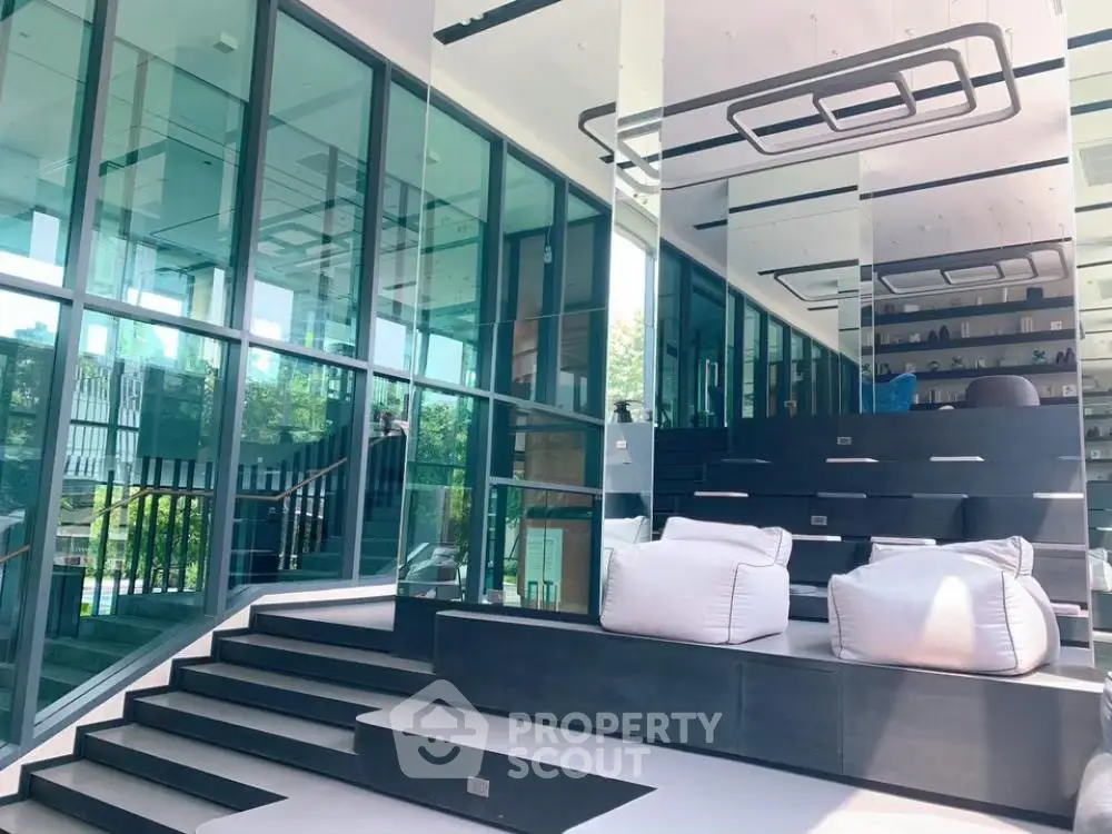Modern living space with sleek black shelves, comfortable white seating, and expansive glass walls offering a seamless indoor-outdoor transition.
