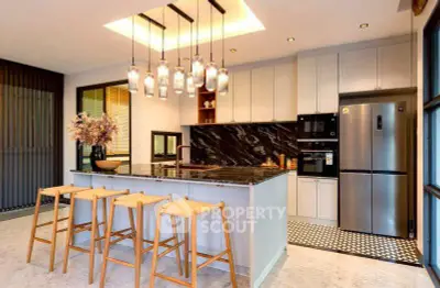 Modern kitchen with sleek design, featuring a large island, stylish pendant lights, and stainless steel appliances.