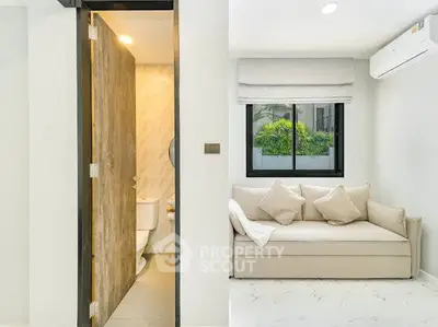 Modern apartment interior with cozy living area and adjacent bathroom, featuring sleek design and natural light.