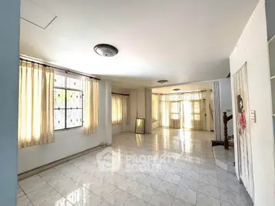 Spacious living room with large windows and tiled flooring