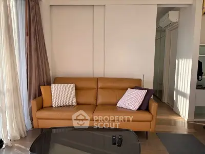 Modern living room with stylish leather sofa and cozy cushions, featuring natural light and elegant decor.