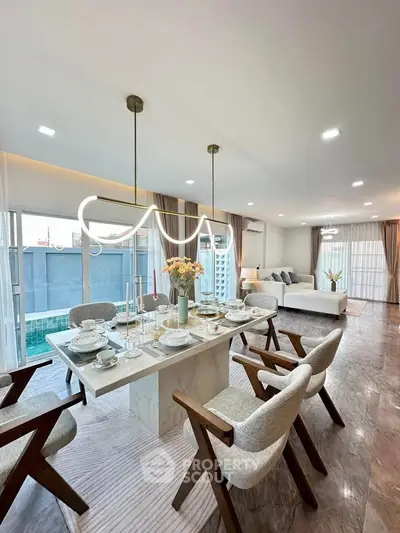 Luxurious open-plan living and dining area with elegant decor and pool view.