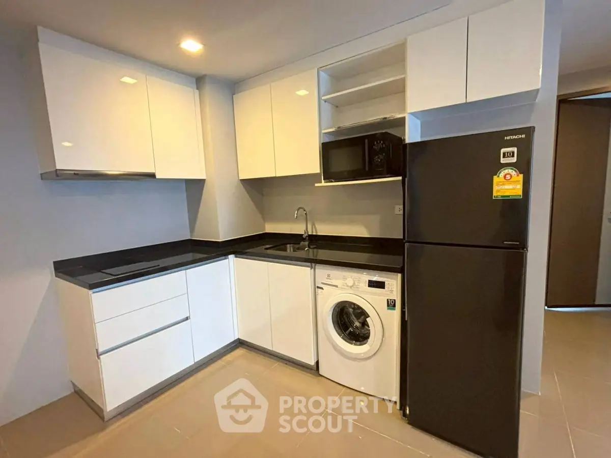 Modern kitchen with sleek white cabinets, black countertops, and built-in appliances.