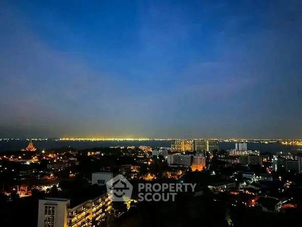 Stunning cityscape view from high-rise building at dusk with sparkling city lights and serene water backdrop.