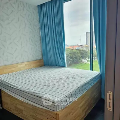 Cozy bedroom with large window offering a scenic city view, featuring modern decor and blue curtains.