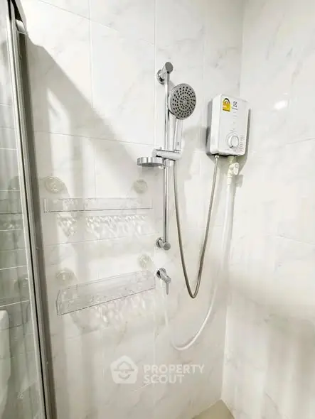 Modern bathroom with shower and water heater in sleek white tiles.