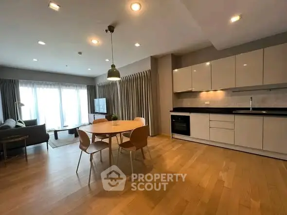 Spacious modern living room with open kitchen and dining area, featuring sleek cabinetry and natural light.