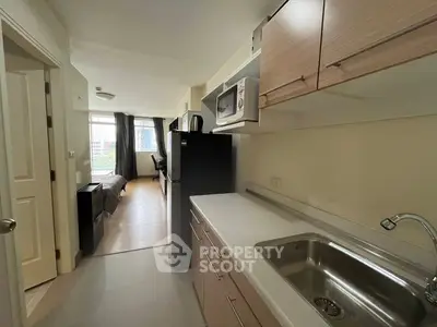 Modern apartment kitchen with sleek cabinetry and open layout leading to living area.