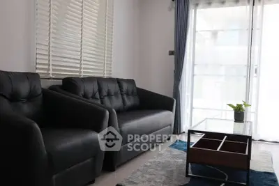 Modern living room with black leather sofas and large window view.
