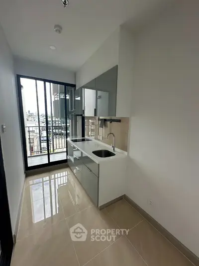 Modern kitchen with sleek cabinetry and balcony view in urban apartment