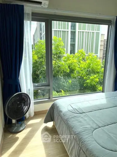 Bright bedroom with large window and lush green view