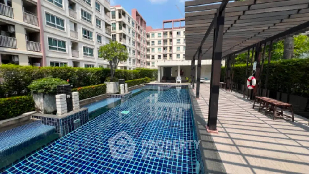 Luxurious condominium with modern pool and shaded seating area, perfect for relaxation and leisure.