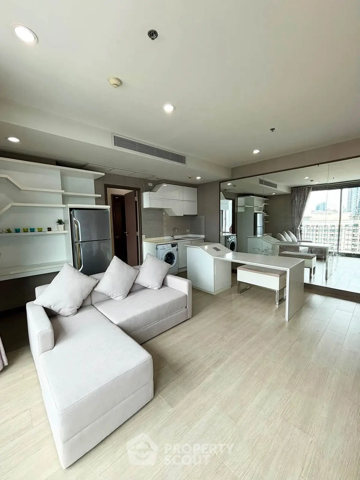 Spacious modern living room with open kitchen and city view, featuring sleek furniture and ample natural light.