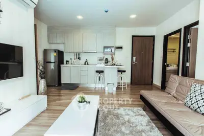 Modern open-layout living room with kitchen, featuring sleek furniture and stylish decor.