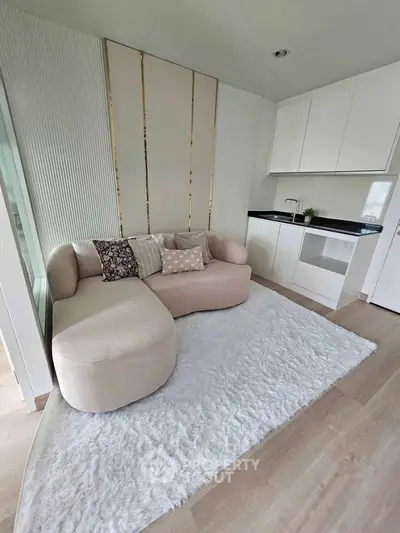 Modern living room with stylish sofa and compact kitchen in open layout design.