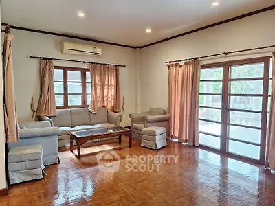 Spacious living room with parquet flooring and large windows for natural light.