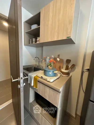 Compact modern kitchen with sleek cabinetry and built-in oven, ideal for urban living.
