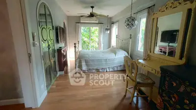Charming bedroom with vintage decor and lush garden view, featuring elegant furnishings and natural light.
