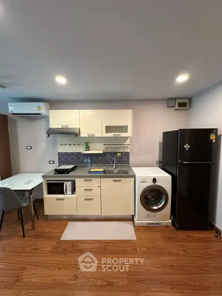Modern kitchen with appliances including washing machine and fridge in a cozy apartment.
