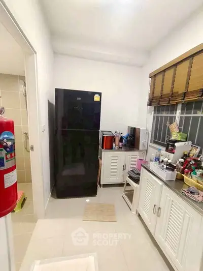 Cozy kitchen with modern black fridge and ample storage space, perfect for culinary enthusiasts.