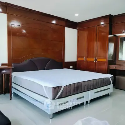 Spacious bedroom with elegant wooden furniture and large bed in modern apartment.