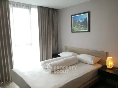 Cozy bedroom with modern decor and natural light, featuring a stylish bed and elegant bedside lamp.