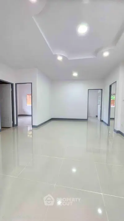 Spacious modern living room with glossy tiled floors and recessed lighting.