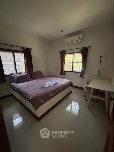 Cozy bedroom with natural light, featuring a comfortable bed and a study desk, perfect for relaxation and work.