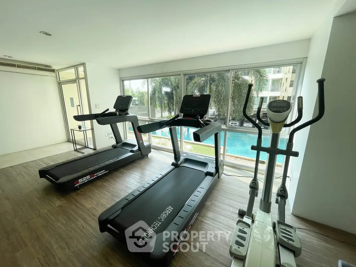 Modern gym with treadmills and pool view in luxury apartment complex