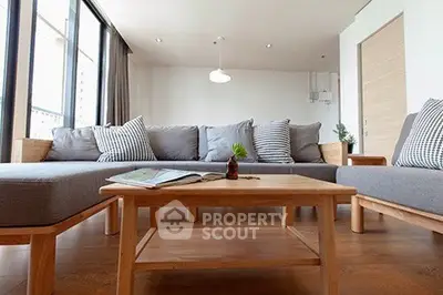 Spacious modern living room with stylish gray sofa and wooden coffee table, perfect for relaxation.