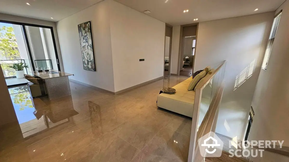 Spacious and modern living room with glossy tile flooring, leading to a sleek open-plan kitchen, abundant natural light, and a cozy balcony with a view.