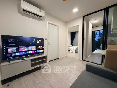 Modern living room with TV and air conditioning, leading to a cozy bedroom.
