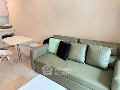 Modern living room with green sofa and dining area in cozy apartment.
