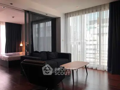 Modern living room with floor-to-ceiling windows and elegant dark furnishings in a high-rise apartment.