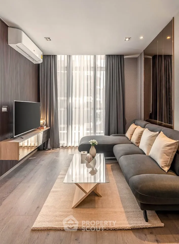 Modern living room with sleek design, featuring a large sectional sofa, wall-mounted TV, and floor-to-ceiling windows.