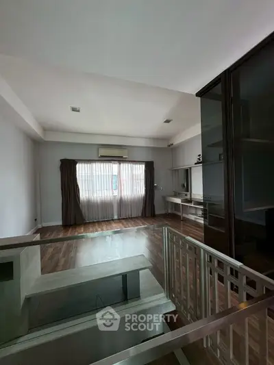 Spacious modern living room with large window and wooden flooring