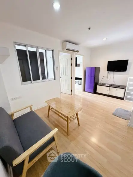 Modern living room with wooden flooring, cozy seating, and wall-mounted TV for a comfortable lifestyle.